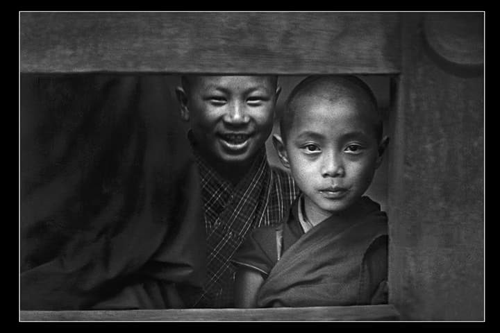 Two young monks in a wooden window frame