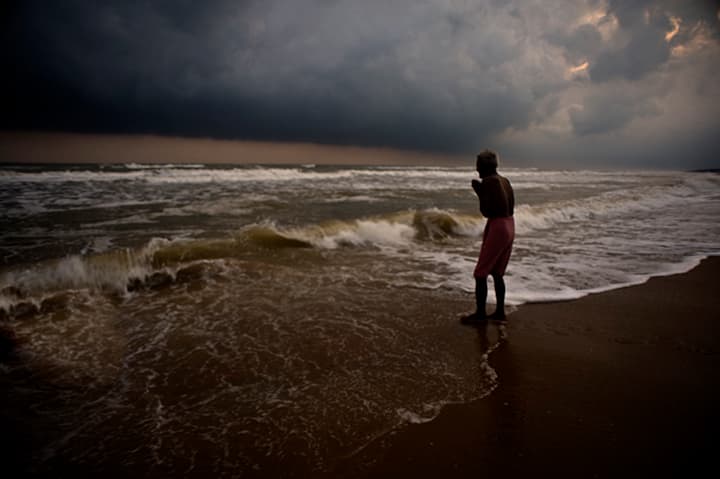 Lone figure praying at storm surf